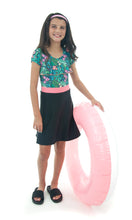 Load image into Gallery viewer, Swim Dress for Girls by Dressing For His Glory. Introduce your daughter to the Swim Dress, available in our Girls Sizes. Made with chlorine-resistant, UPF 50+ swimwear fabric, this dress is perfect for swimming and beach activities. Featuring a scooped neckline, cap sleeves, and a charming ruffle on the front yoke, the dress comes with attached bike shorts under the skirt for added comfort. Stay cool and stylish in this must-have piece.